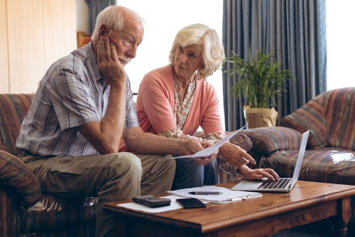 MId adult support worker explaining medical details to senior couple at home. Mature friendly woman working as social worker, talking to old man and woman for insurance plans on retirement. Happy supporter with senior people during a home consultation: counseling and psychological session at home.